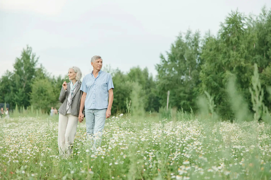 A senior couple enjoying a peaceful walk through a lush flower field on a sunny day
