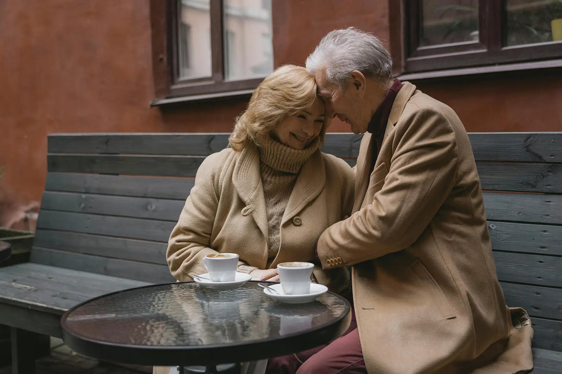 Lovely elderly couple sharing coffee on a cozy outdoor bench, expressing warmth and affection.