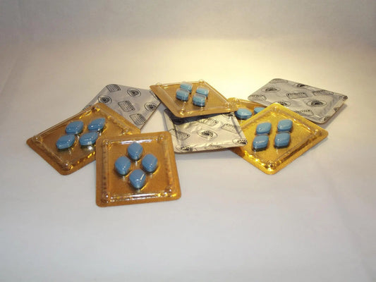 Several packets of blue sildenafil tablets (generic Viagra) used for erectile dysfunction treatment laying on a white surface.